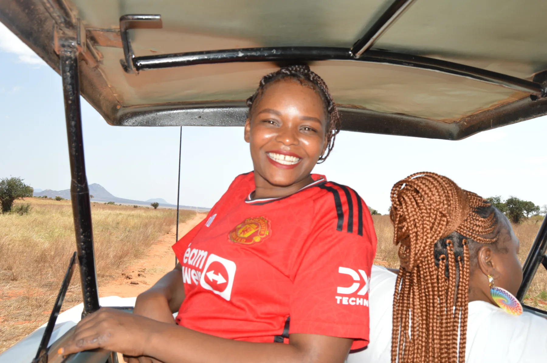 A smiling guest standing in the open roof hatch of a safari van