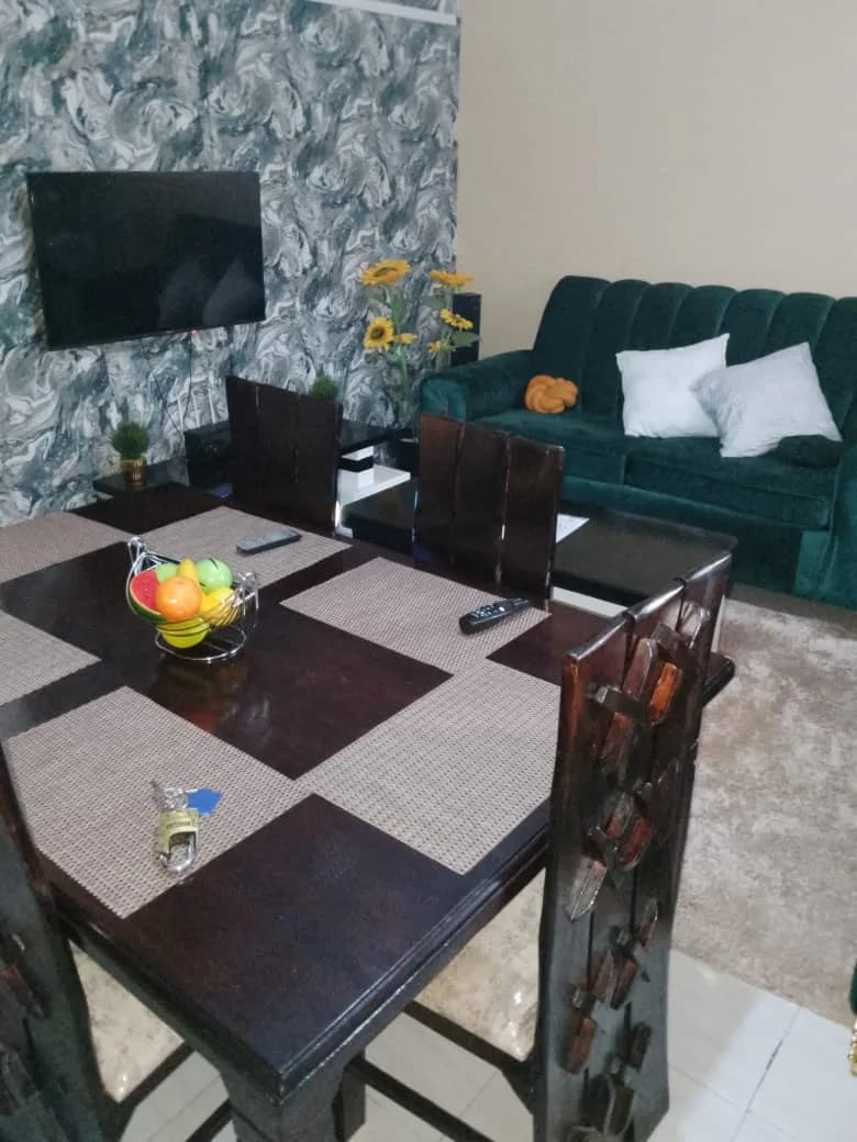 A living and dining room with a green sofa in the Diani apartment